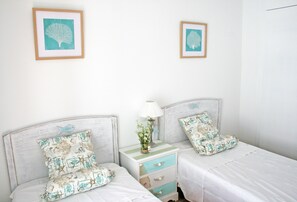 A bedroom with two beds, each with matching decorative pillows and a small bedside table with a lamp. - Pet-Friendly Apartment with Sea View, Balconies & A/C (El Port de la Selva)