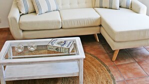 A living room with a sectional sofa, a glass coffee table, and two abstract paintings on the wall. - Pet-Friendly Apartment with Sea View, Balconies & A/C (El Port de la Selva)
