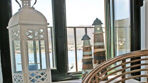 A wicker chair with a striped pillow, a white lantern, and a view of a lighthouse through a window. - Pet-Friendly Apartment with Sea View, Balconies & A/C (El Port de la Selva)