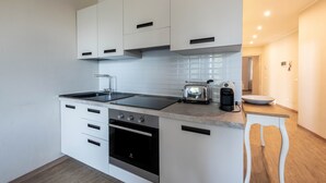 A modern kitchen with white cabinets, a black stove, and a toaster. - Lo Scorcio sul Lago (Salò)