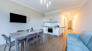 A modern apartment with a dining area, kitchenette, and a living room with a sofa. - Lo Scorcio sul Lago (Salò)
