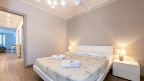 A modern bedroom with a large bed, bedside lamps, and a ceiling fan. - Lo Scorcio sul Lago (Salò)