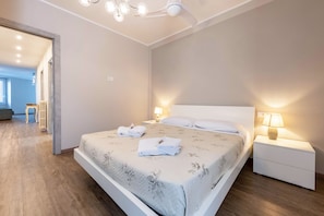 A modern bedroom with a large bed, bedside lamps, and a ceiling fan. - Lo Scorcio sul Lago (Salò)
