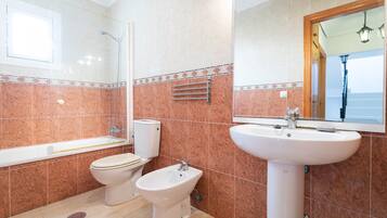 A bathroom with a bathtub, toilet, bidet, and sink.