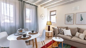 Una sala de estar moderna con una mesa de comedor redonda, sillas blancas, un sofá beige y una pequeña mesita auxiliar.