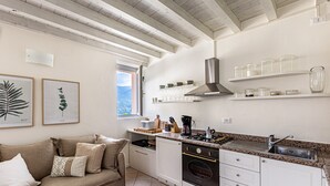Una cocina con gabinetes blancos, una estufa y un ventanal.