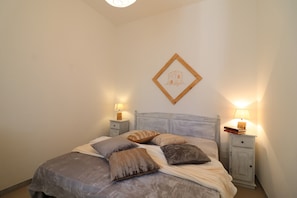 A bedroom with a bed, two bedside tables, and a wall-mounted picture.