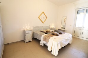 Une chambre à coucher comprenant un lit, des tables de chevet, une commode, un miroir et un tableau accroché au mur.