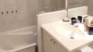 A bathroom with a bathtub, a glass-enclosed shower, a sink with a mirror, and a toilet.