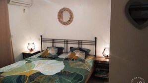 A bedroom with a bed, two bedside lamps, an air conditioner, a wall-mounted mirror, and a heart-shaped decoration.