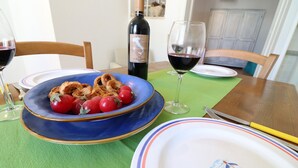 A dining table with plates, a bottle of wine, and a glass of wine. - Apartment "Casa Vacanza Locorotondo Otranto" with Garden, Shared Pool & Wi-Fi (otranto)