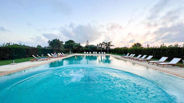A rectangular swimming pool with lounge chairs on both sides, surrounded by greenery and trees. - Apartment "Casa Vacanza Locorotondo Otranto" with Garden, Shared Pool & Wi-Fi (otranto)