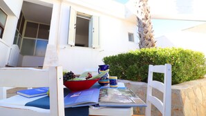 A white building with a balcony, a table with a bowl of fruit, a book, and a cup. - Apartment "Casa Vacanza Locorotondo Otranto" with Garden, Shared Pool & Wi-Fi (otranto)