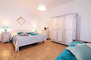 A bedroom with a bed, nightstands, a wardrobe, and a hanging light fixture.