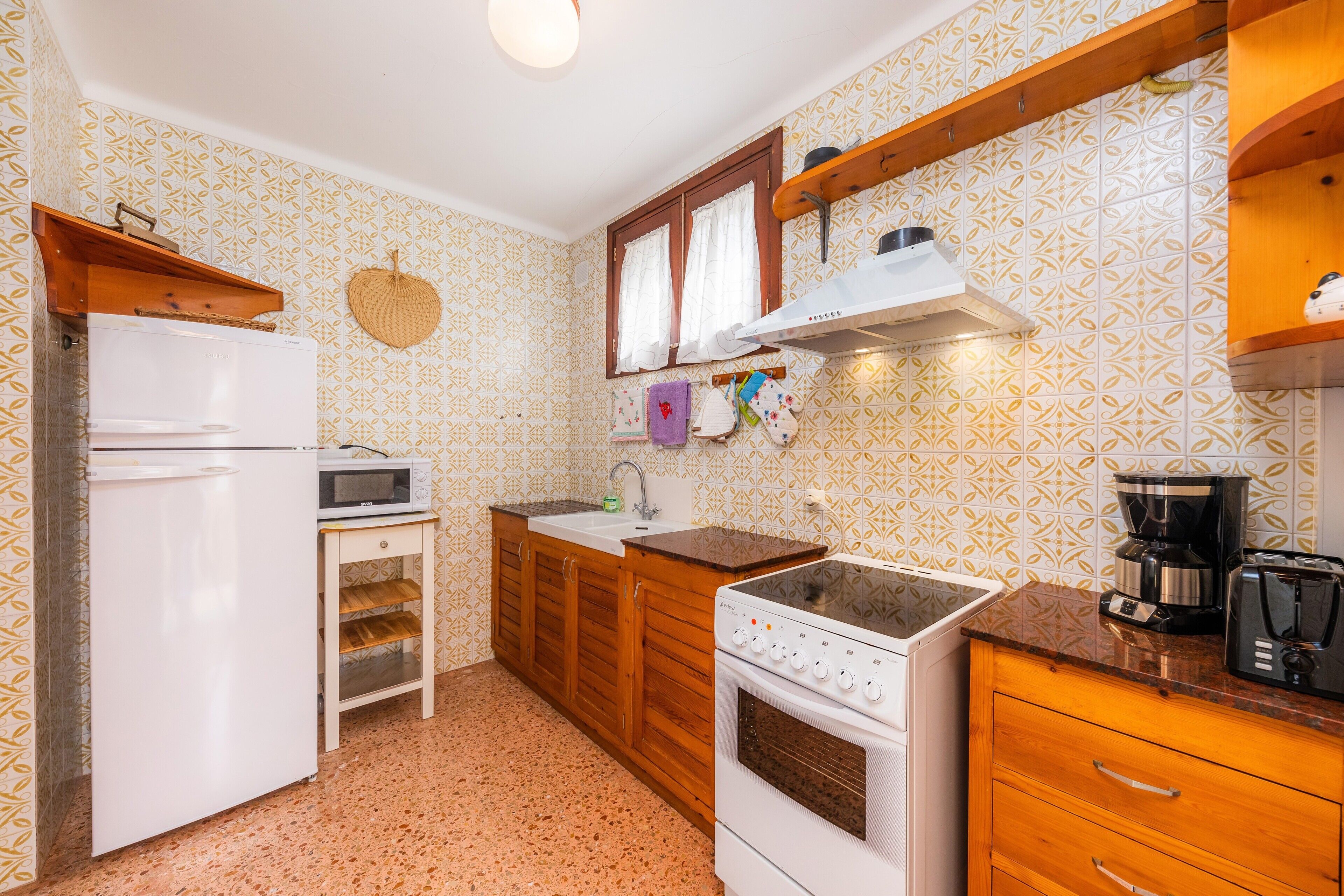 Een kleine keuken met een koelkast, magnetron, oven en koffiezetapparaat.