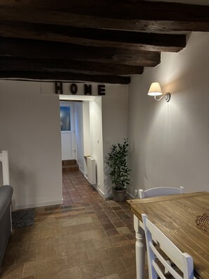 Ein schmales Entree mit Holzboden, einem Schild mit der Aufschrift „HOME“, einer Topfpflanze und einem Tisch mit Stühlen.
