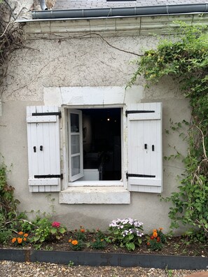 Ein rustikales Gebäude mit kleinem Fenster, umgeben von einem Garten mit verschiedenen Blumen.