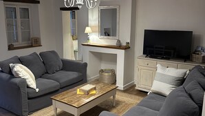 A living room with a dark grey sofa, a wooden coffee table, and a television. - Les Hortensias, 3-star self-catering cottage, heated pool, wifi, games... (Monteaux)