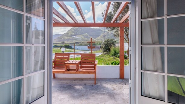 A room with a wooden bench and a view of a mountainous landscape through a large window.