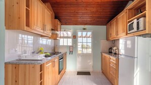 A kitchen with wooden cabinets, a white refrigerator, and a microwave.