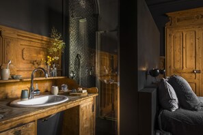 Un baño con tocador de madera, lavamanos y zona de ducha.