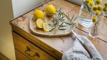 Una mesa de madera con tabla de cortar, limones, romero y un cuchillo.