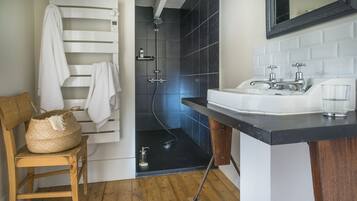 A modern bathroom with a shower, a sink, and a wooden chair with a woven bag.