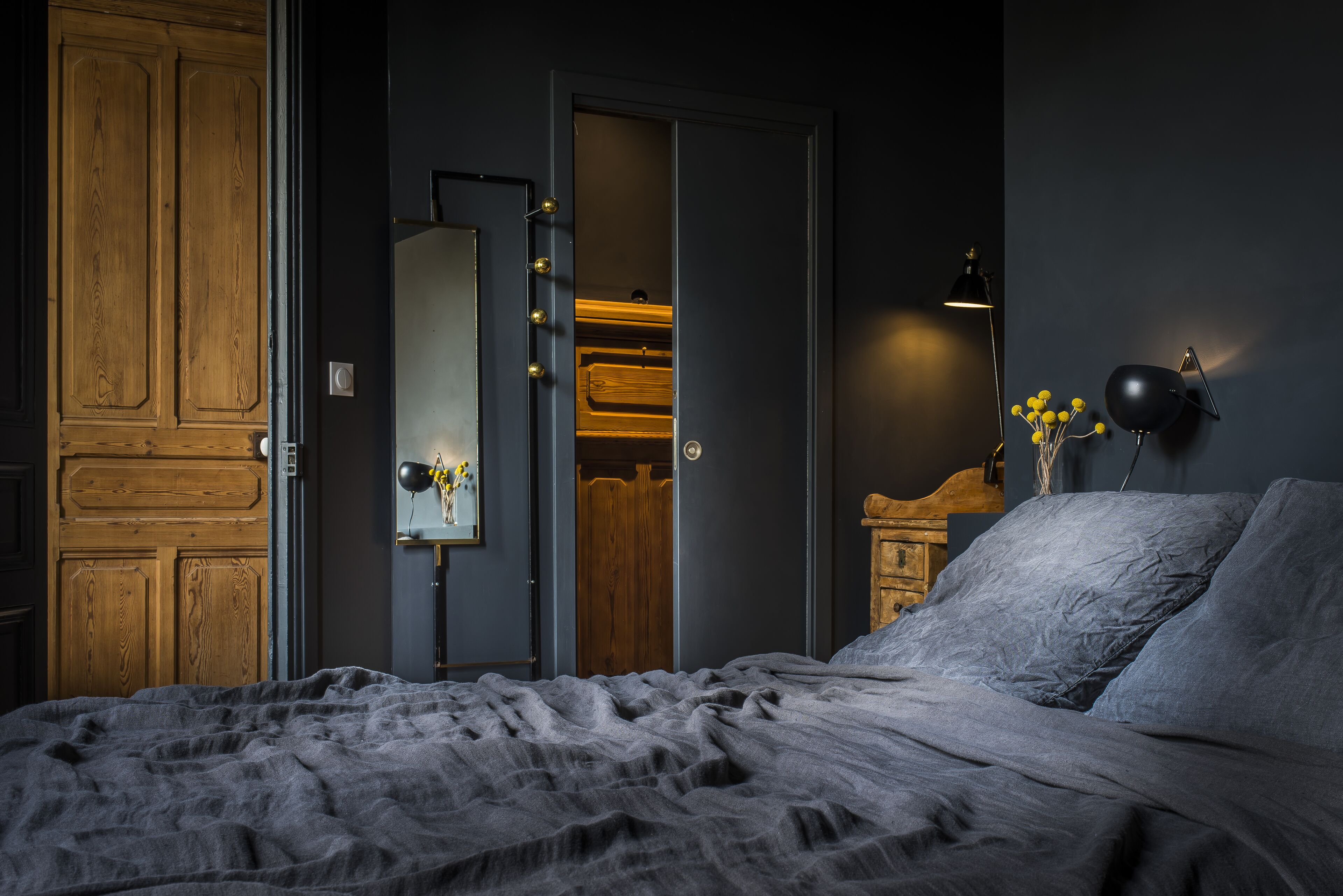 Ein Schlafzimmer mit Bett, Kleiderschrank, Spiegel und einer Wandlampe.