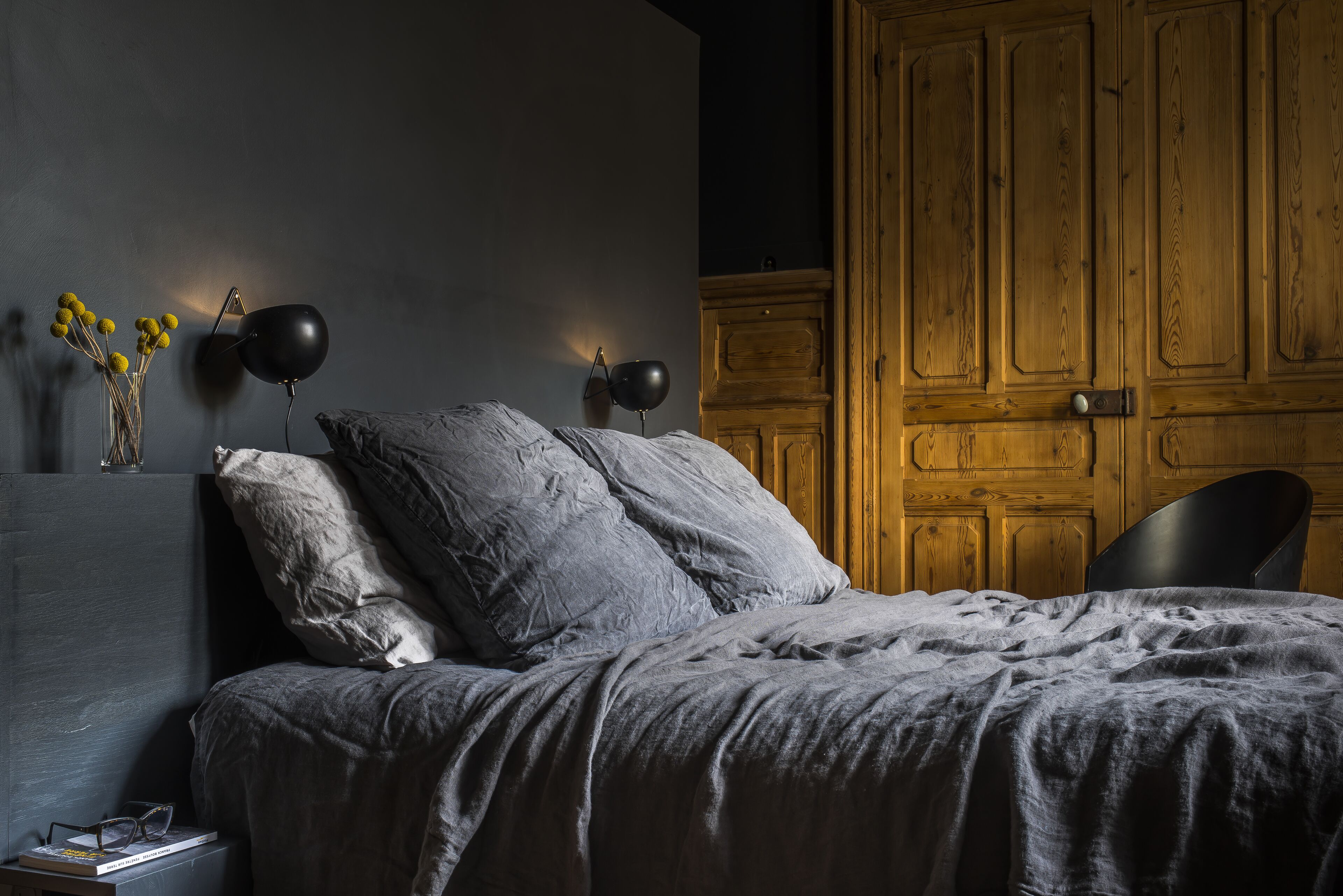 Un dormitorio con cama, dos lámparas de noche, una mesita de noche y un armario de madera.