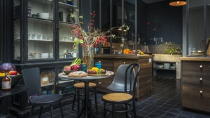 A modern kitchen with dark wood cabinets, a central island with stools, and a large window with a view of the city. - Le Secret (Saint-Martin-de-Re)