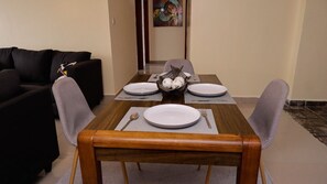 A dining area with a wooden table set for four, surrounded by grey upholstered chairs.