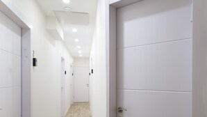 A hallway with white doors, a light wooden floor, and recessed ceiling lights. - Aju Ben Yehuda 23 (Jerusalem)