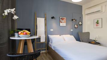 Un dormitorio con una cama, una mesita con fruta, una silla, una escalera y un aire acondicionado instalado en la pared.