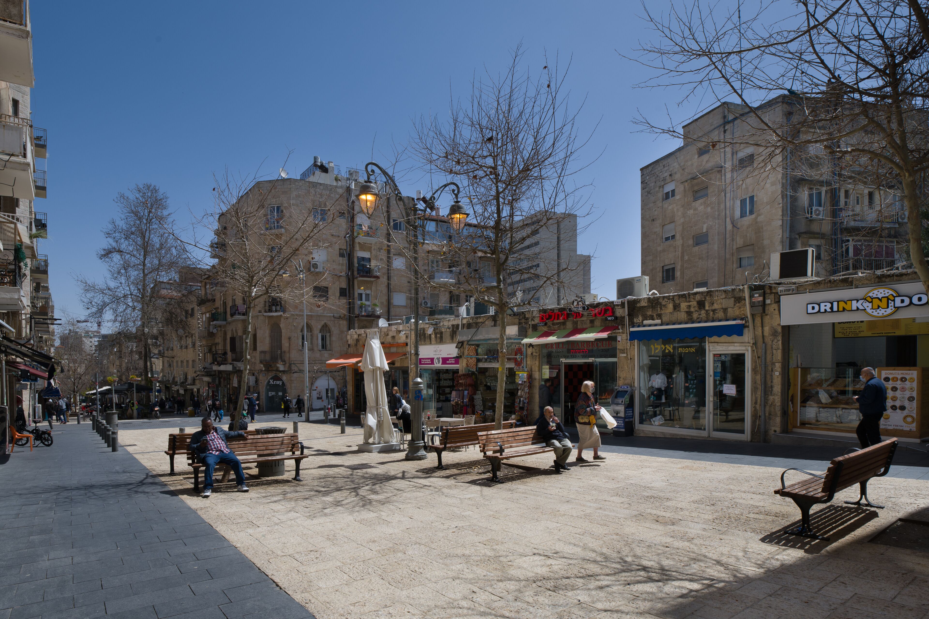 A public square with benches, a statue, and buildings with shops.