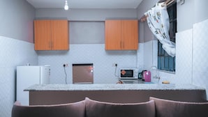 Una cocina compacta con dos armarios de madera, un refrigerador blanco, un microondas y un lavamanos.