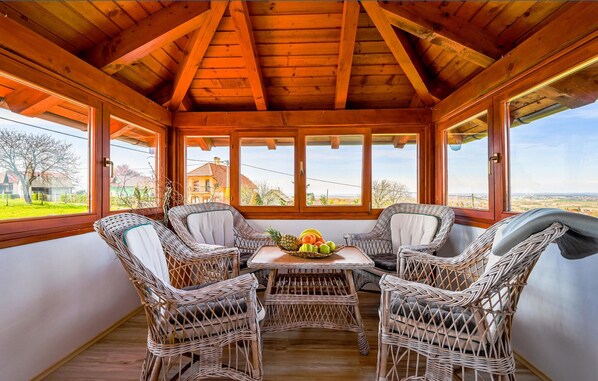 Relax in a serene space with a view of the surrounding landscape, featuring a comfortable seating area with a table and wicker chairs.