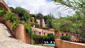 Una escalera de piedra conduce a una zona de piscina rodeada de exuberante vegetación y arquitectura tradicional.
