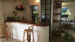 Una cocina rústica con una barra, dos taburetes de madera y un florero con flores.