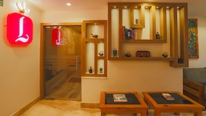 A hotel lobby with a modern design, featuring a prominent red neon sign, wooden shelves with decorative items, and a seating area with two tables. - Lords Eco Inn Kathmandu (Kathmandu)