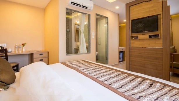 A hotel room with a bed, a desk, a chair, a TV, and a bathroom visible through a glass door. - Lords Eco Inn Kathmandu (Kathmandu)