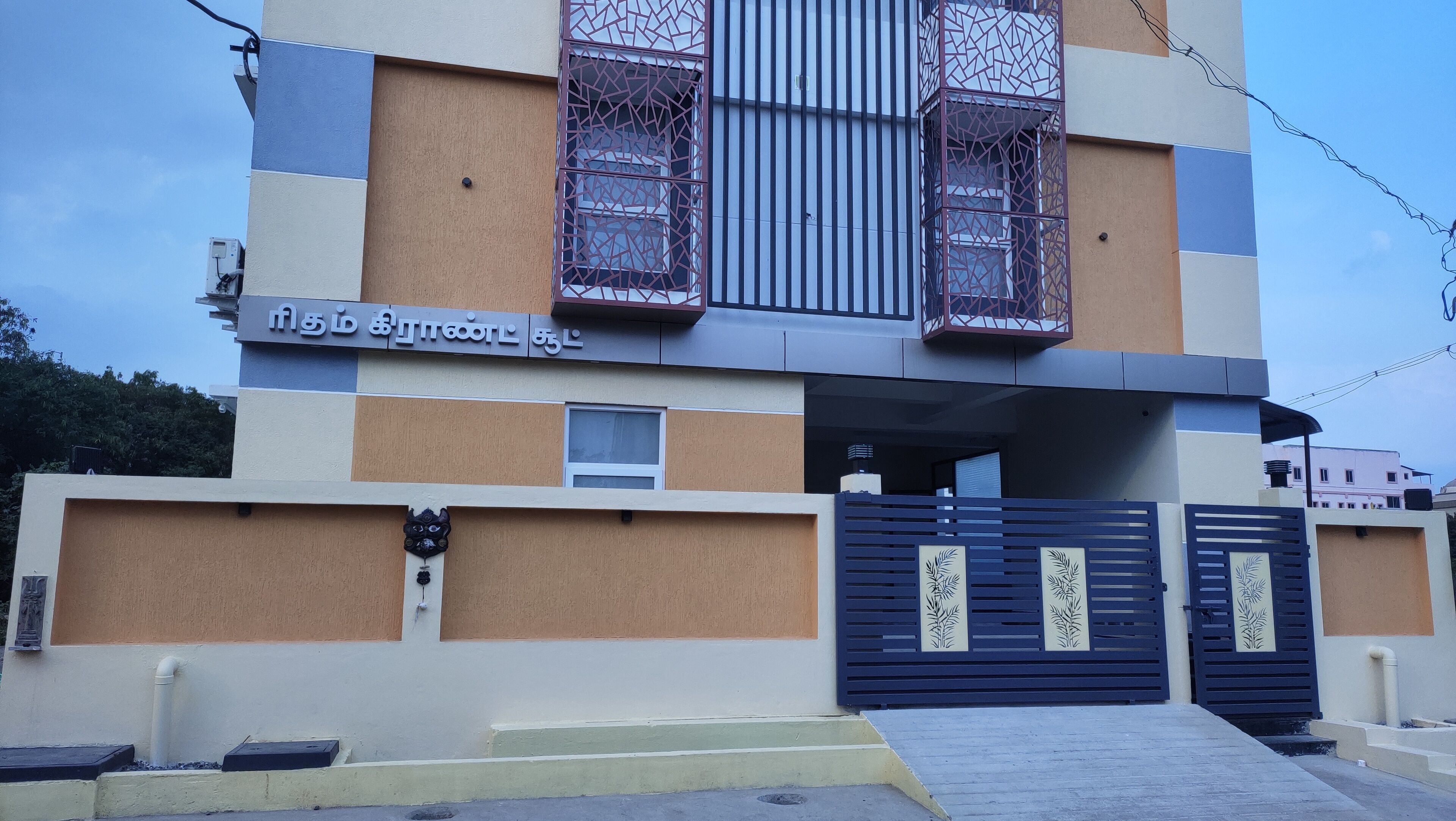A modern building with a large entrance, a gated driveway, and a sign in a foreign language.