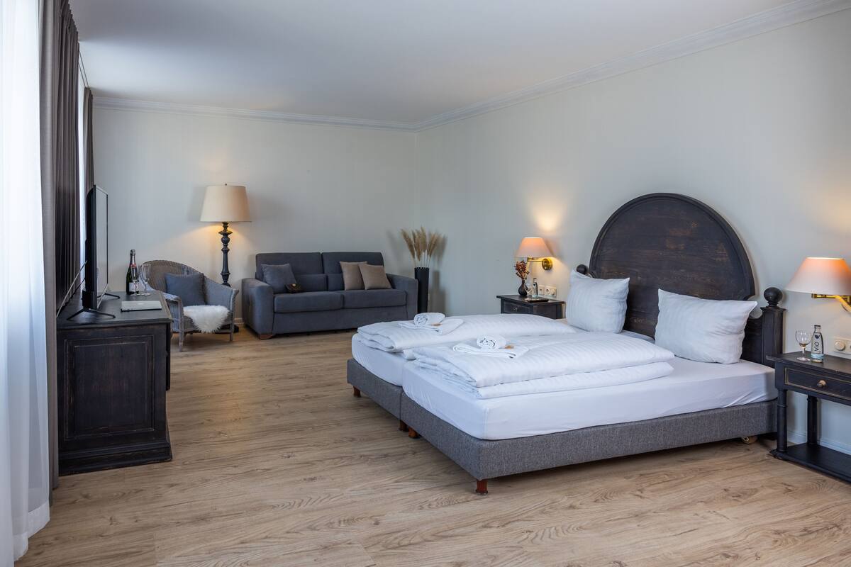 A hotel room with a large bed, a sofa, a desk, and a TV.