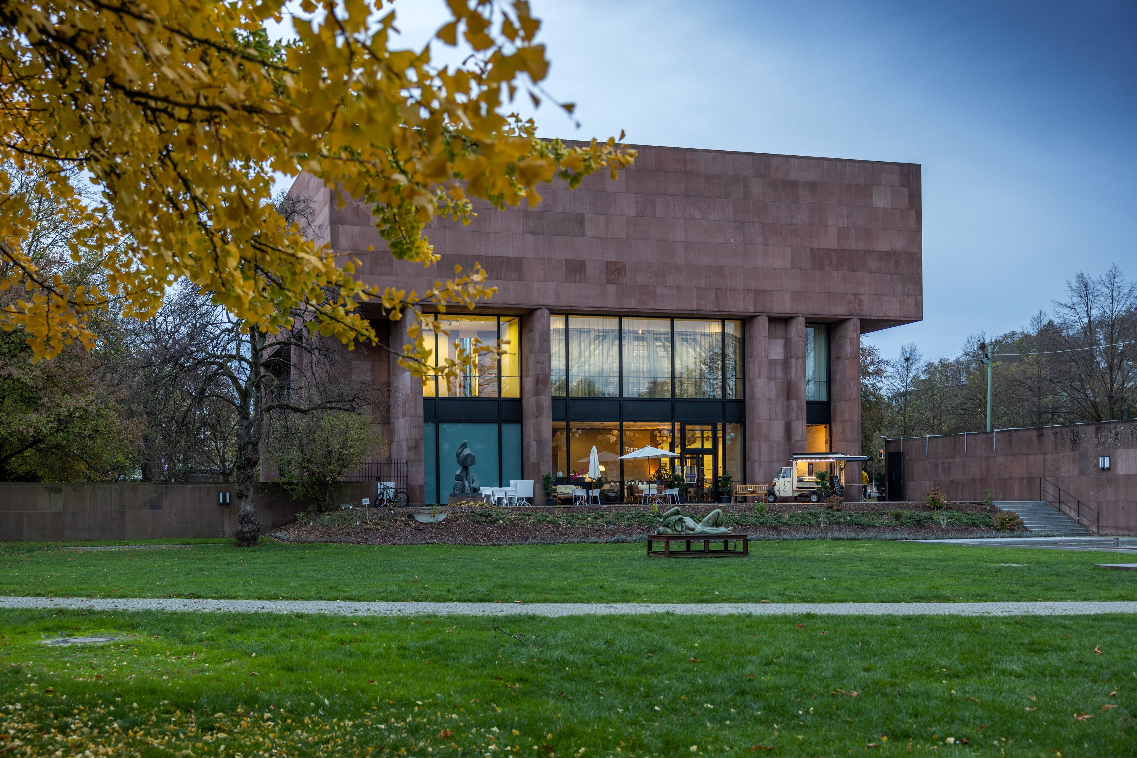 A modern building with large windows and a paved courtyard.