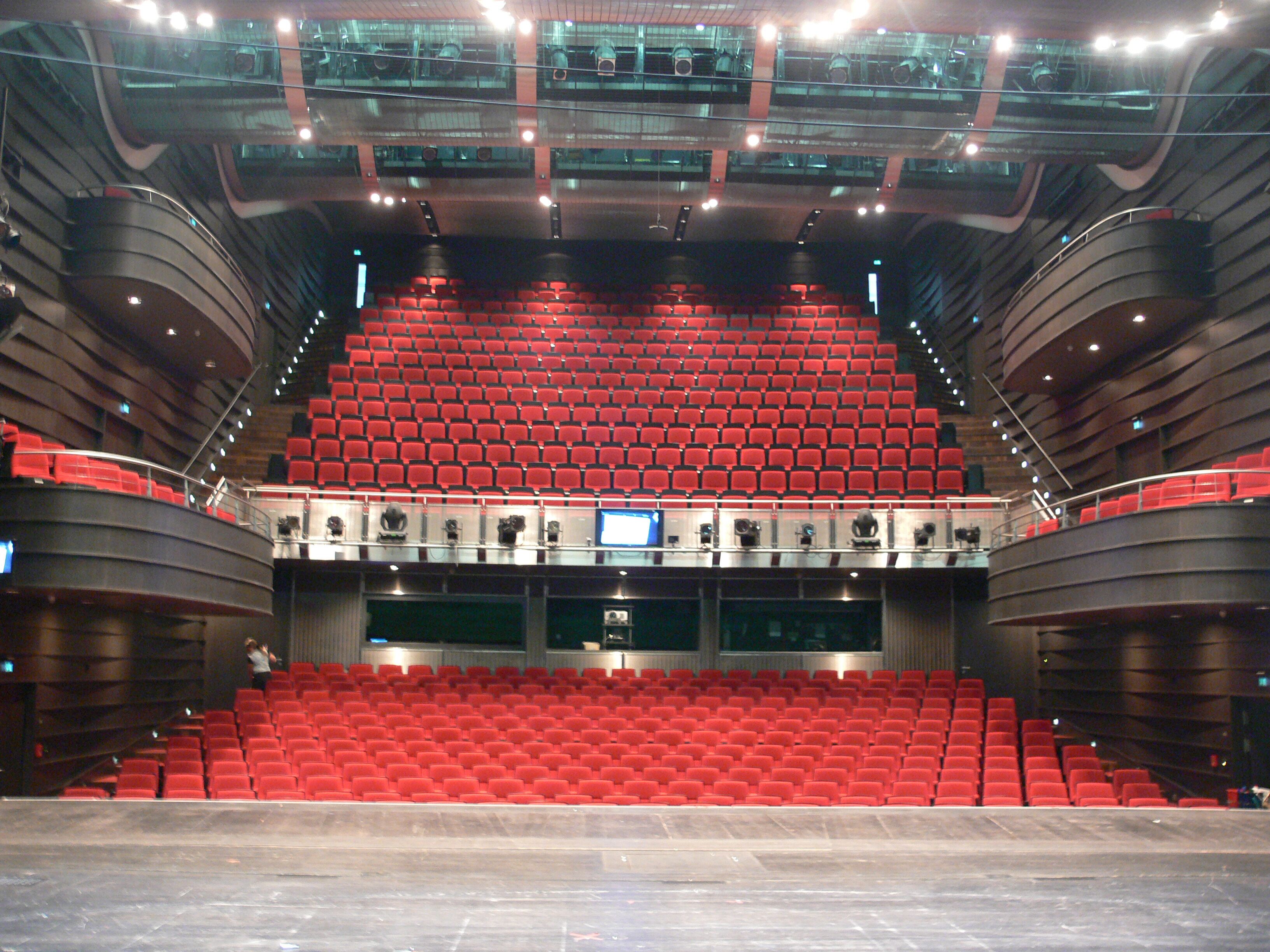 Une grande salle de conférence dotée de gradins et d’une scène à l’avant.
