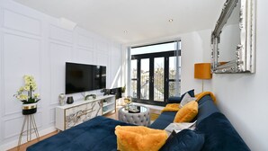 Un salon moderne doté d’un grand téléviseur, de sièges confortables, d’une cheminée en marbre et d’un balcon offrant une vue imprenable.