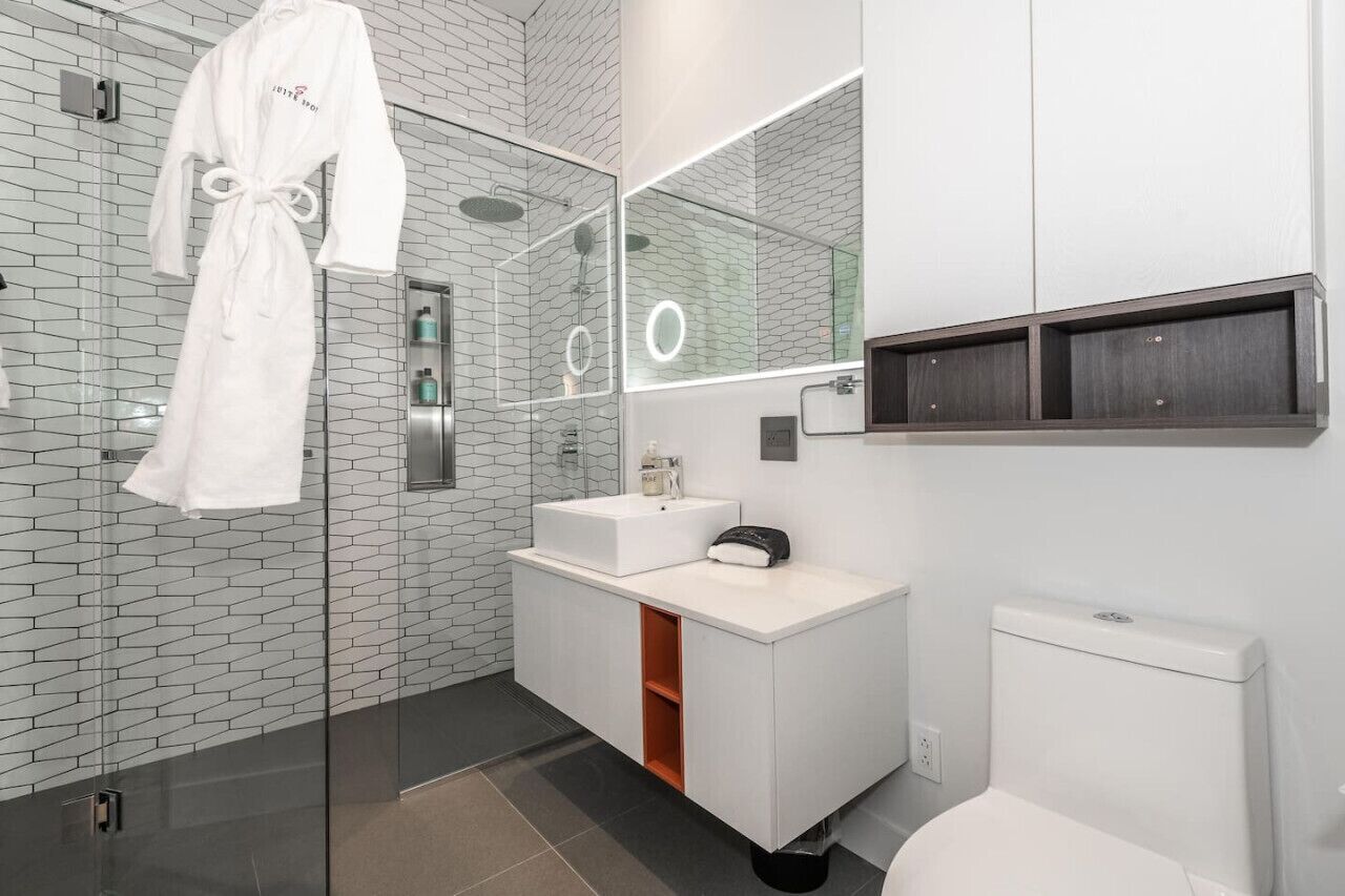 A modern bathroom with a glass shower enclosure, a white vanity with a mirror, and a white toilet.