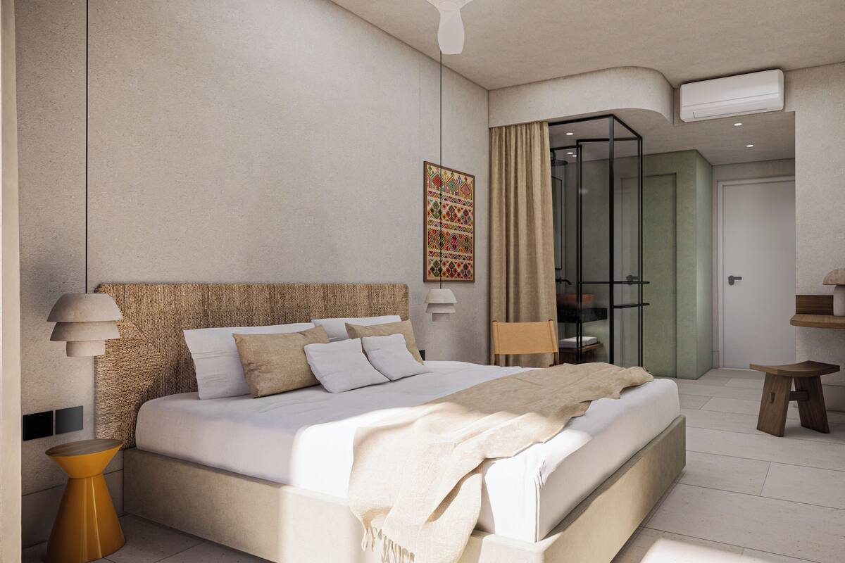 Una habitación de hotel moderna con una cama grande, una mesita auxiliar pequeña, una lámpara y un televisor.