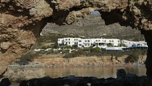 A coastal view with a building complex and beach umbrellas. - Cavo Marelia (Karpathos)