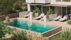 A modern outdoor pool area with lounge chairs and a covered seating area. - Cavo Marelia (Karpathos)