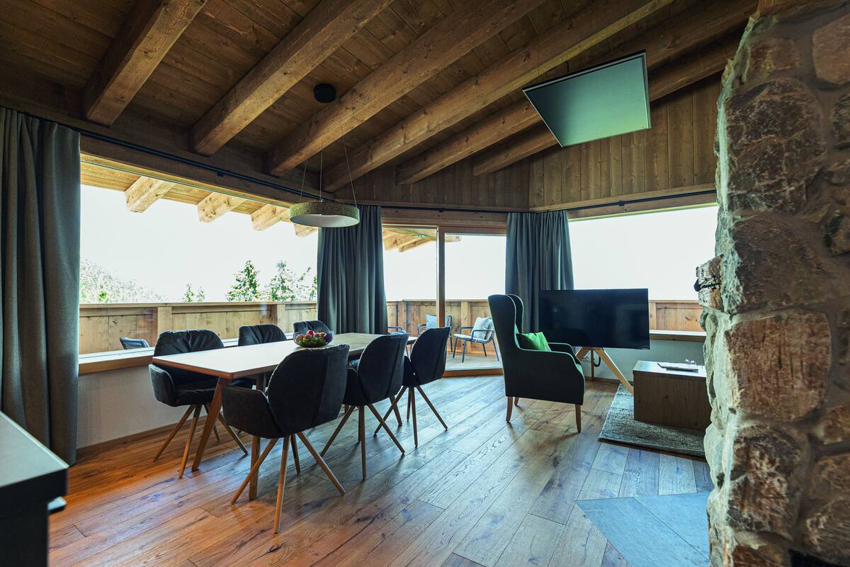 Ein Essbereich mit Holztisch und -stühlen, einem Fernseher und einer Steinwand.